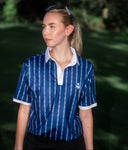 Woman wearing a blue patterned shirt with a blurred green background